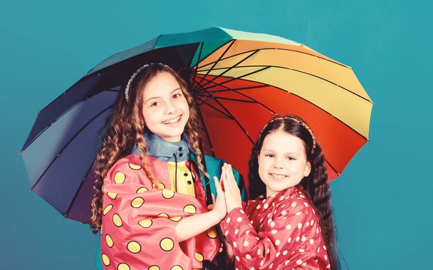 rain protection. Rainbow. autumn fashion. happy little girls with colorful umbrella. cheerful hipster children, sisterhood. family bonds. Little girls in raincoat. Any weather is good - Photo, Image