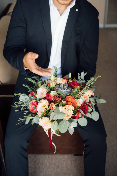 the groom waits for the bride and holds in hands a beautiful wedding bouquet - Photo, Image