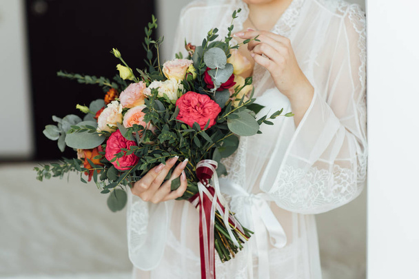 bride in a white dress holding a bouquet of flowers and greenery - Фото, изображение