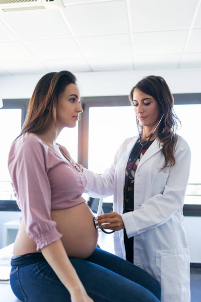 Kaunis nuori nainen gynekologi tarkkailun syke vauva hänen raskaana oleva potilas klinikalla
. - Valokuva, kuva