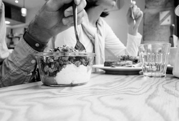 Müsli d ile lezzetli yoğurt yiyen kadın ve erkeğin yan görünümü - Fotoğraf, Görsel