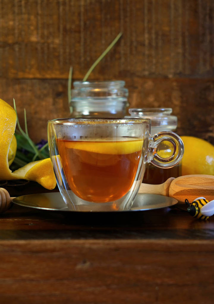 Honey and lemons served with a cup of tea on rustic wood background. - Photo, Image