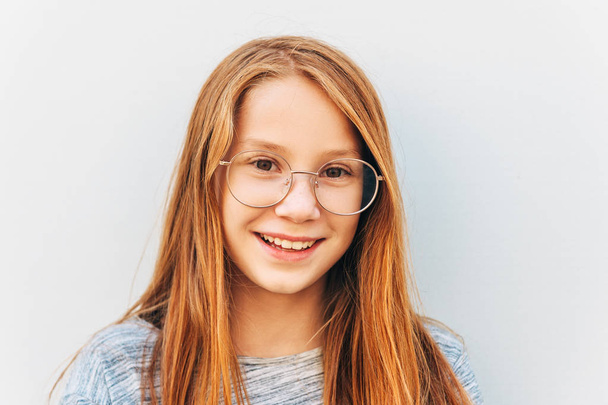 Υπαίθριο πορτρέτο του γλυκού κοριτσάκι με κόκκινα μαλλιά, φορώντας γυαλιά - Φωτογραφία, εικόνα