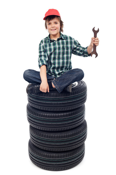 Young mechanic with tires and spanner - Foto, Bild