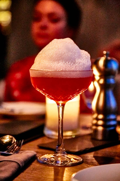 Rosafarbener Cocktail mit großer Schaumstoffkappe. - Foto, Bild