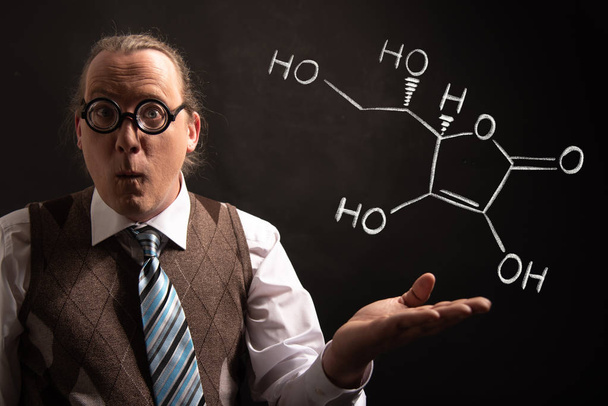 Profesor presentando fórmula química dibujada a mano de la vitamina C
 - Foto, imagen