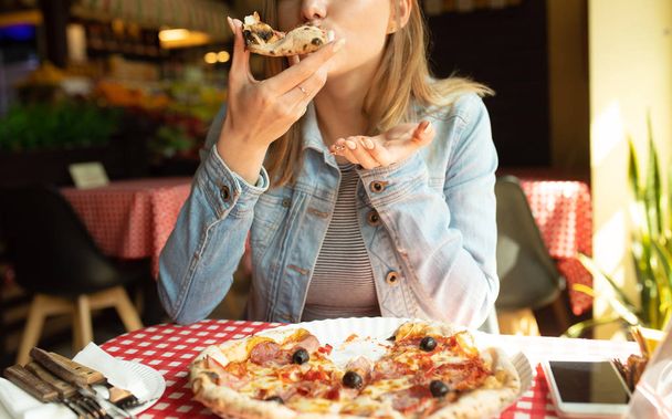 Portrait of blonde woman eating fresh baked pizza in cafe - Foto, Imagen