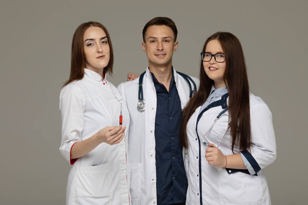 Successful team of medical doctors standing together on gray background. - Фото, изображение