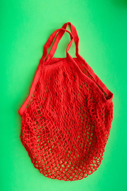 Red shopping mesh bag on green background. Zero waste concept and plastic free concept. - Foto, immagini