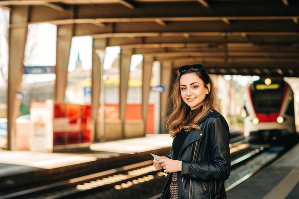 Fiatal nő várja a vonat egy vasútállomás - Fotó, kép