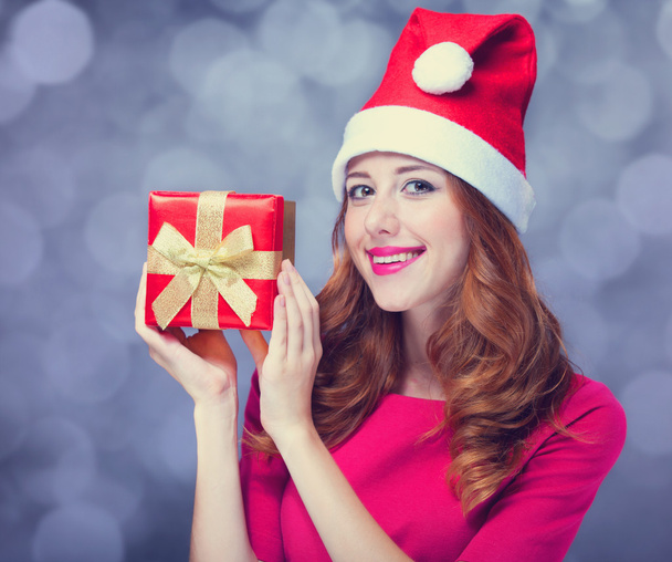 κοκκινομάλλα κοπέλα με καπέλο Χριστούγεννα με δώρο. - Φωτογραφία, εικόνα
