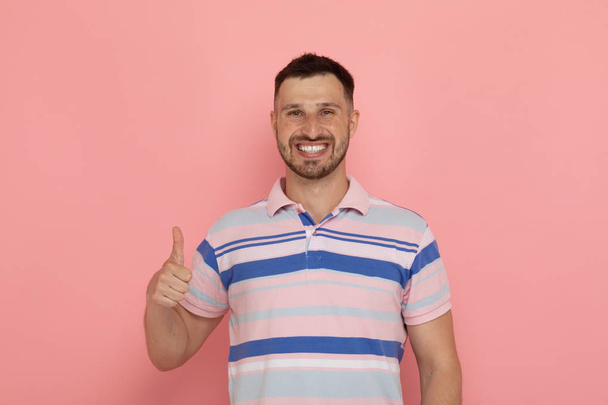 Young cheerful man showing thumb up posing on pink background - Φωτογραφία, εικόνα
