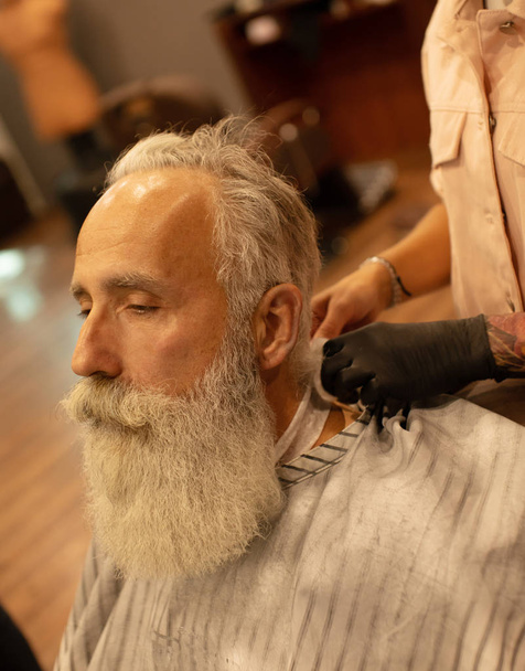 Senior man visiting hairstylist in barber shop. - Zdjęcie, obraz