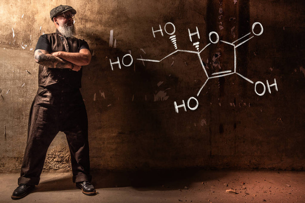 Hombre viejo barbudo que presenta fórmula química dibujada a mano de vitamina C
 - Foto, Imagen