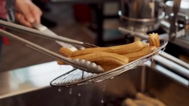 cook holds ready churro over hot bowl to drip extra oil - Filmagem, Vídeo