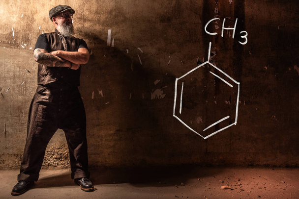 Hombre viejo barbudo que presenta fórmula química dibujada a mano de tolueno
 - Foto, imagen