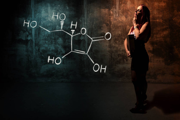 Sexy chica o secretaria o estudiante que presenta fórmula química dibujada a mano de vitamina C
 - Foto, imagen