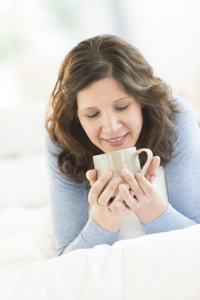 Woman Drinking Coffee While Relaxing In Bed - Foto, imagen