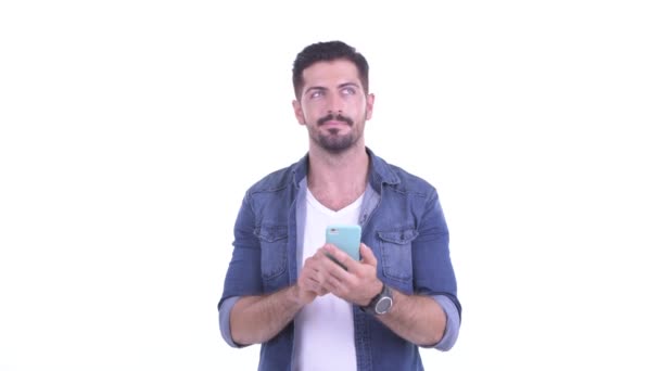 Feliz joven barbudo hipster hombre pensando mientras usa el teléfono - Metraje, vídeo