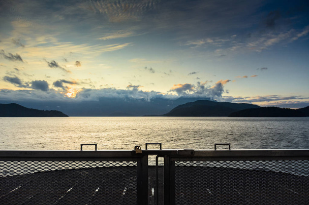 Salida del sol sobre el océano y las montañas desde la cubierta del ferry, Howe Sound cerca de Gibsons, Canadá
. - Foto, Imagen