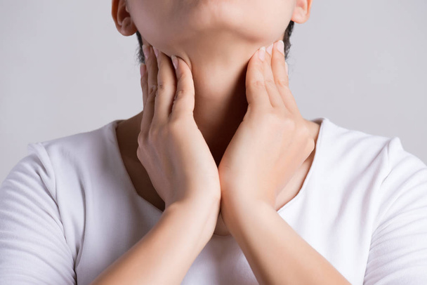 Pijnlijke keel. Een close-up van mooie jonge vrouw die haar nek aanraakt. Gezondheidszorg en medisch concept. - Foto, afbeelding