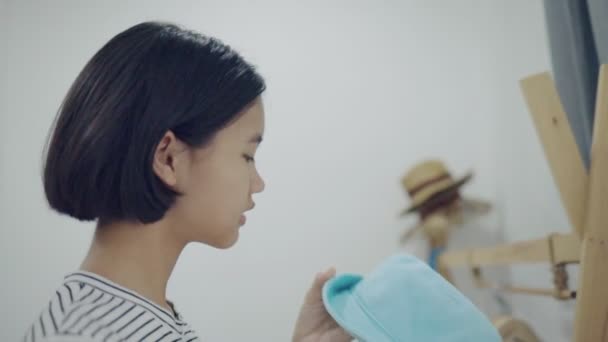 Lovely Asian girl trying a hat in front of the mirror, Slow motion - Filmagem, Vídeo