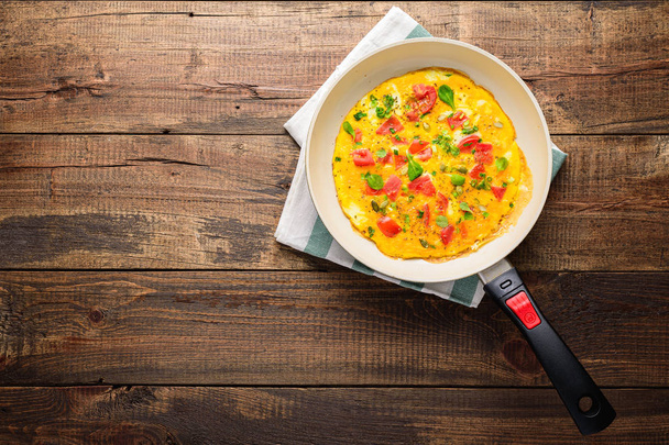 Omelette with tomatoes and herbs in rustic style in griddle. Frittata - italian omelet. - Fotó, kép