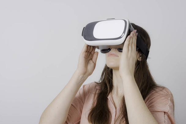 Жінка за допомогою VR пристрою тримається в обох руках і дивиться вгору
. - Фото, зображення