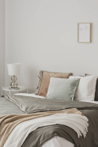 Colorful pillows in king size bed with duvet and blankets in hygge inspired bedroom - Fotografie, Obrázek