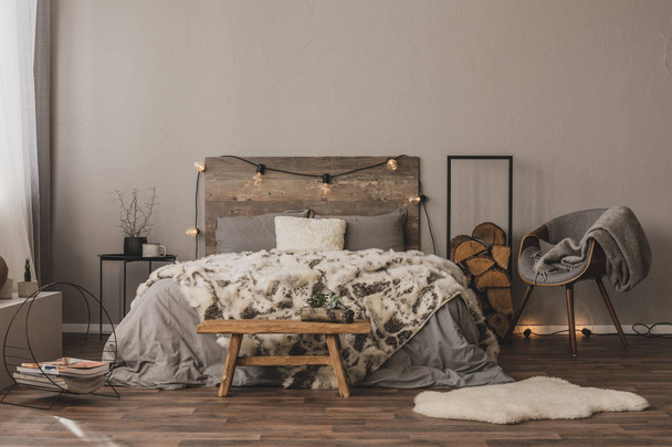 Copy space on empty grey wall of stylish bedroom interior with wooden accents and king size bed - Фото, изображение