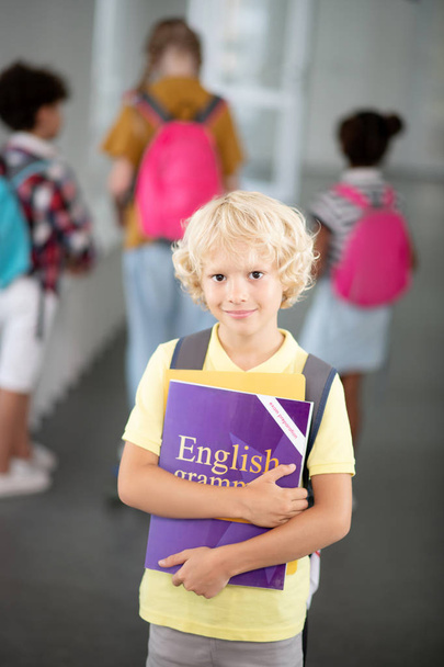 Ξανθιά μαθητής κρατώντας αγγλικό γραμματικός βιβλίο - Φωτογραφία, εικόνα