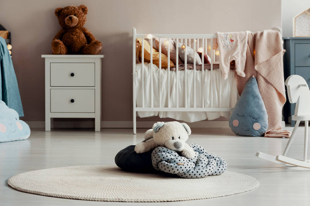 Osito de peluche blanco en almohada punteada en el suelo del dormitorio de bebé de moda
 - Foto, imagen