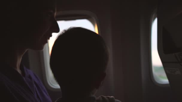 Mom with a child sits at the window of the plane while the plane starts to take off - Πλάνα, βίντεο