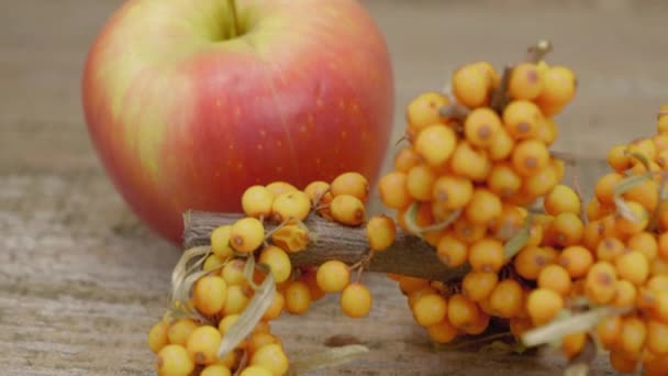Apples and branch of sea buckthorn. Also on the table are star anise stars and cinnamon sticks on a wooden surface. Close-up. - Footage, Video