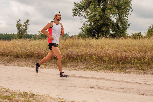 自然の中でスポーツユニフォームであごひげで屋外を走っている男、日、野外 - 写真・画像