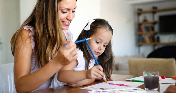 Little girl painting with her mother together at home - Foto, imagen