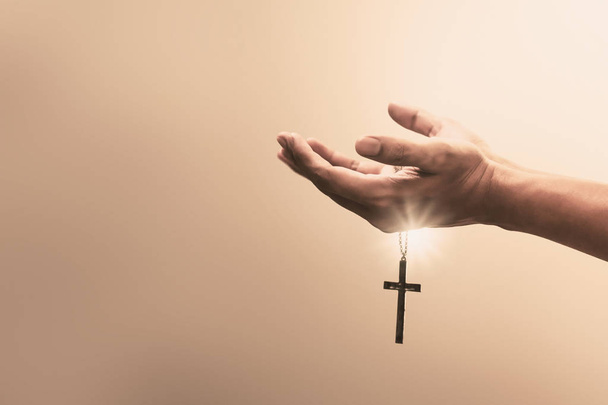 Ręce modląc się trzymać krzyż Krzyża metalowego naszyjnik z wiarą w religię i wiarę w Boga na tle spowiedzi. Moc nadziei, miłości i oddania. - Zdjęcie, obraz