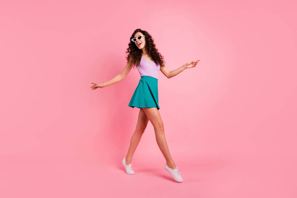 Full length body size photo of turned charming excited careless nice cute girl wearing singlet walking during her vacation while isolated over pastel background - Foto, afbeelding