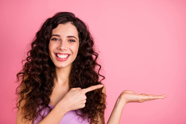 Photo of cheerful cute charming pretty girlfriend pointing at object in on her palm while isolated with pink background - Photo, Image