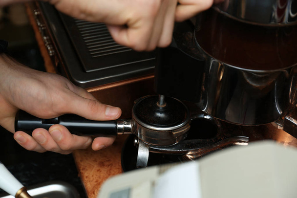 Barista pressing ground coffee with tamper in portafilter, closeup - Photo, Image