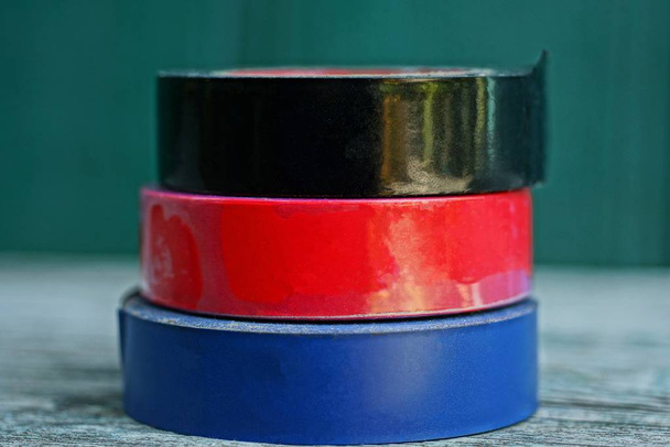 un conjunto de rollos de color de cinta eléctrica se encuentra en una mesa gris
 - Foto, Imagen