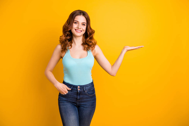 Photo of cute wavy curly cheerful fascinating pretty sweet girlfriend wearing turquoise tank-top jeans denim holding something invisible with her hand while isolated with vibrant color background - Fotografie, Obrázek