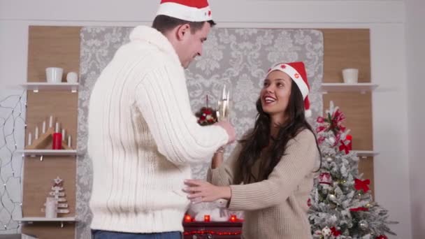 Caucasian couple dancing and drinking champagne in Christmas decorated room - Felvétel, videó