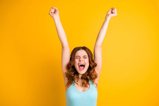 Photo of wavy curly shouting grimacing pretty cute girlfriend expressing her rejoicing with face wearing teal singlet while isolated with yellow background - Фото, изображение