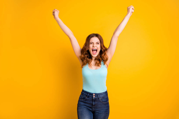 Photo of curly wavy crazy beautiful attractive rejoicing overjoyed girlfriend wearing turquoise tank-top jeans denim grimacing while isolated with yellow vivid color background - Foto, Bild