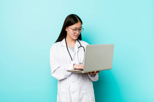 Joven asiática médico mujer holding un laptop
 - Foto, imagen