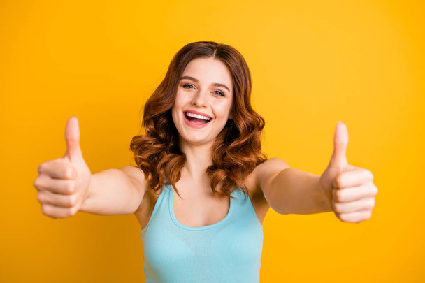 Photo of cute charming beautiful cheerful girlfriend showing you thumb up wearing turquoise singlet while isolated with yellow vibrant color background - Fotó, kép