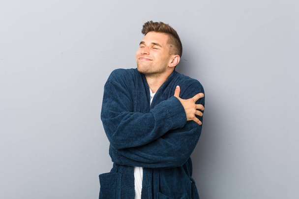 Young caucasian man wearing pajama hugs, smiling carefree and happy. - Photo, Image