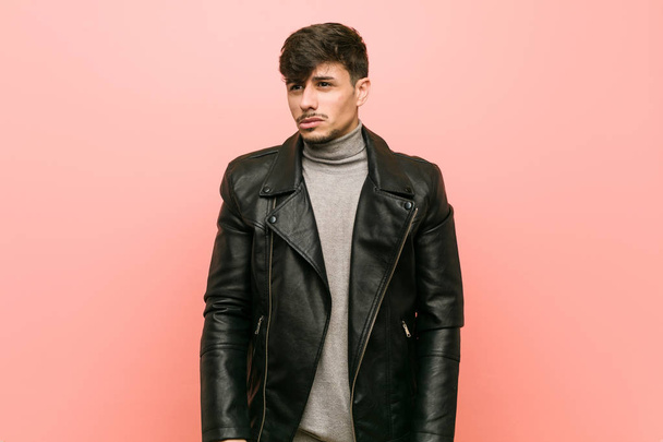 Young hispanic man wearing a leather jacket confused, feels doubtful and unsure. - Foto, Bild