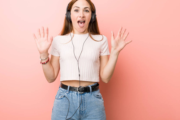 Joven mujer caucásica escuchar música celebrando una victoria o éxito
 - Foto, Imagen